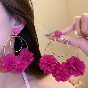 Close-up detail of pink chiffon flower drop earrings with golden double hoops on ear