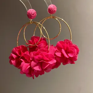Detail showing pink chiffon flower pendant earrings with raffia studs and gold hoop
