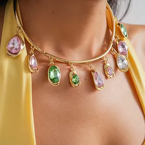 Detailansicht einer Goldkette mit rosa und grünen Edelsteinen in Tropfenform am Modell.