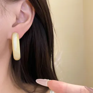 Detailed macro view of a cream yellow resin hoop earring on an Asian model's ear
