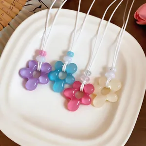 Gros plan de quatre colliers fleurs en résine colorée : violet, bleu, rose et crème.