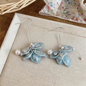 Close-up of elegant petal earrings with pearls and shimmering zircons in light blue.