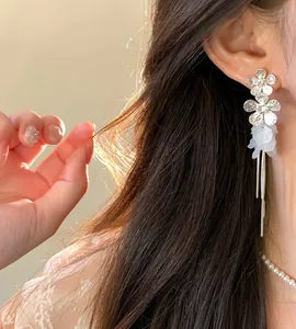 Elegant detail shot of silver needle zircon flower tassel earrings with white petals