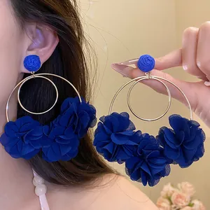 Close-up of royal blue chiffon flower hoop earrings with raffia studs for vacation style