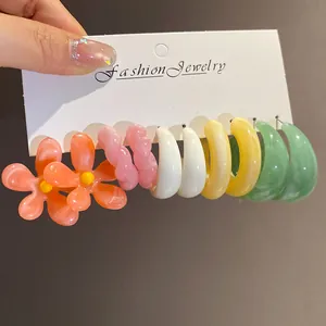 Detailed view of colorful resin flower and geometric hoop earrings set on a white card