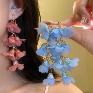 Close-up detail of bohemian style long fabric flower tassel earrings in pink and blue