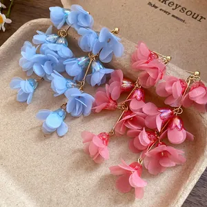 Detailed view of pink and blue chiffon flower drop earrings on a kraft tray