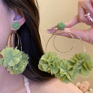 Detail showing green raffia and chiffon flower pendant earrings with gold hoops