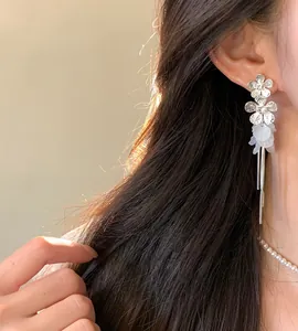 Elegant close-up of silver flower tassel earrings with white petals on a model's ear