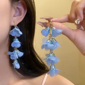 Close-up of layered blue fabric flower earrings with silver needles for summer vacation.