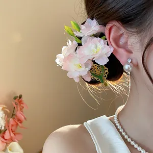 Vista dettagliata di un'elegante clip per capelli con fiori in tessuto rosa su uno chignon