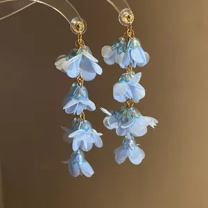 Macro view of blue chiffon flower dangling earrings with iridescent bead accents
