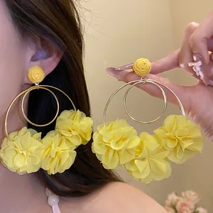 Macro view of yellow chiffon flower drop earrings with a golden double hoop design