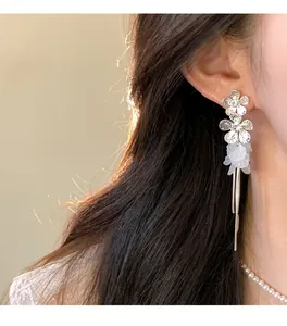 Macro view of silver-toned flower tassel earrings with delicate white petal details