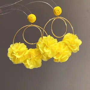 Close-up detail showing yellow chiffon flower pendant earrings with raffia woven studs