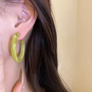 Close-up of lime green resin geometric hoop earring worn for high-fashion detail.