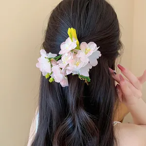 Dettaglio di un fermaglio per capelli in tessuto rosa con fiori di ciliegio su capelli scuri.