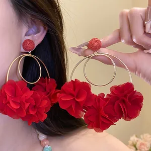 Detail of large red chiffon flower earrings with golden hoops on an Asian model