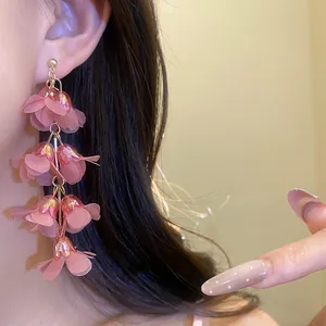 Macro detail of bohemian pink fabric flower dangling earrings for vacation outfits