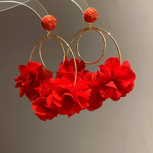 Detailed macro view of vibrant red chiffon flower petals and gold hoops on raffia earrings