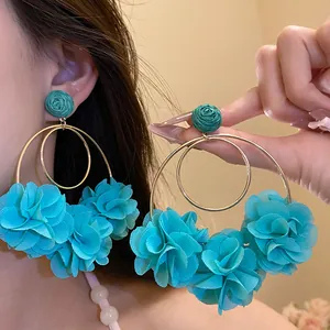 Close-up of bohemian teal chiffon flower drop earrings with raffia rose stud detail