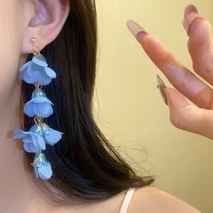 Close-up of elegant blue fabric flower drop earrings in bohemian style for summer vacation