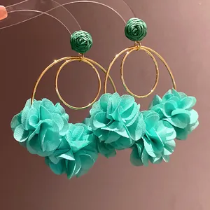Detailed close-up of teal chiffon flower earrings with gold hoops and raffia accents