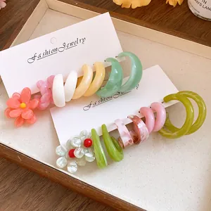 Detailed view of colorful resin geometric and flower earrings on display cards