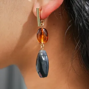 Detailed macro view of retro geometric resin drop earrings with amber and marble beads