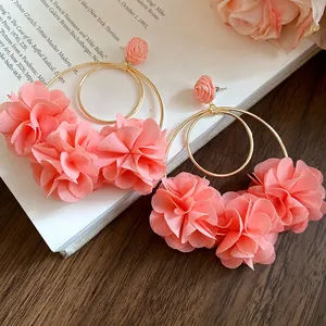 Detailed close-up view of elegant pink chiffon flower hoop earrings on a vintage book