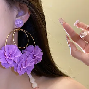 Close-up of purple chiffon flower pendant earrings with gold hoops on female model