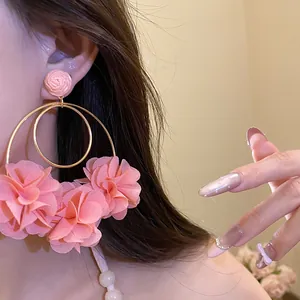 Close-up detail of oversized pink chiffon flower hoop earrings on a model