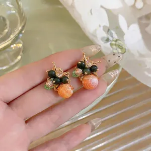 Eleganti orecchini a lobo a grappolo di fiori in vetro con design unico di frutta dorata.