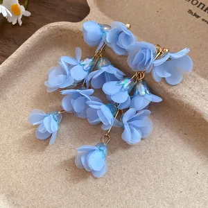 Close-up of bohemian light blue fabric flower tassel earrings with iridescent beads