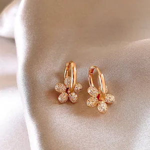 Close-up of 14k gold plated earrings with crystal-encrusted flower pendant detail.