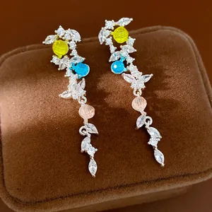 Detail view of silver earrings with colorful gems and leaf-shaped cubic zirconia