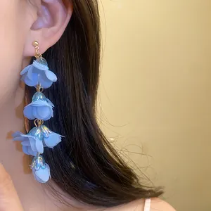 Detailed shot of long blue fabric flower earrings for a bohemian seaside vacation look.