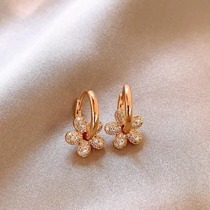Detailed view of 14k gold plated flower hoop earrings with shimmering cubic zirconia.