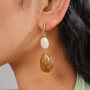 Close-up of vintage resin drop earrings with brown marbled beads on a model's ear