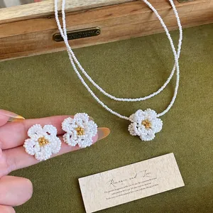 Dettaglio del set di gioielli con orecchini e collana camelia in perle bianche