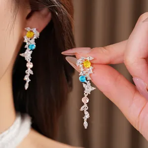 Close-up detail of silver leaf tassel earrings with colorful cubic zirconia inlays