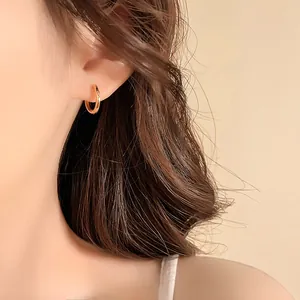 Close-up of an elegant 14k gold plated small hoop earring worn on a model's ear