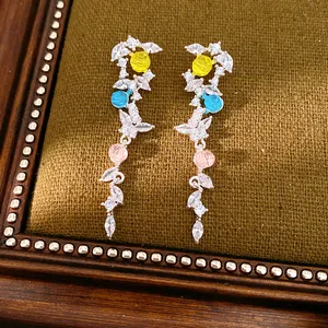 Detail of silver needle tassel earrings with colorful stones and leaf zircon accents.