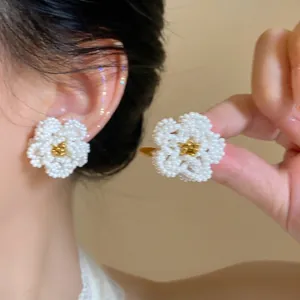 Dettaglio di orecchini a forma di camelia in perle bianche fatti a mano.