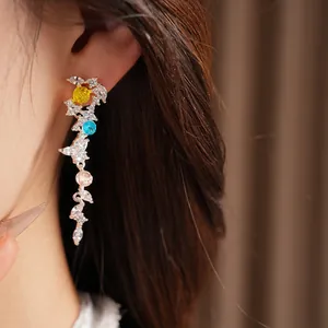 Detailed view of silver needle leaf tassel earrings with colorful zircons on a model.