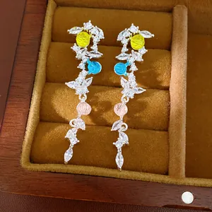 Detailed view of elegant zircon leaf tassel earrings with colorful round beads in a box.