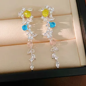 Elegant close-up of zircon leaf tassel earrings with colorful stones in a jewelry box