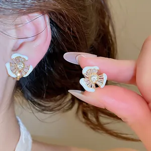 Nahaufnahme von 18k vergoldeten Emaille-Blumen-Ohrclips mit glänzenden Zirkon-Details.