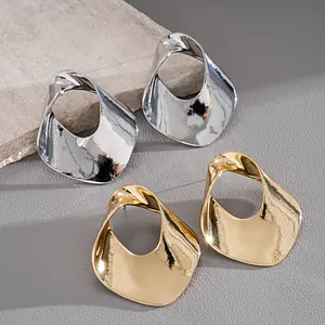 Detailed view of hollow circular metal stud earrings in gold and silver metallic finishes