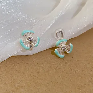 Nahaufnahme von cyanfarbenen Blumen-Ohrclips mit 18 Karat Vergoldung und Zirkonia
